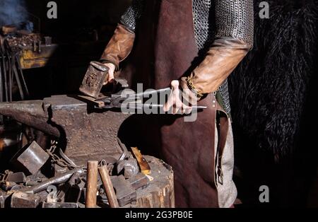 Viking forge des armes et des épées dans le smithy. Un homme dans les vêtements d'un guerrier est dans le smithy Banque D'Images