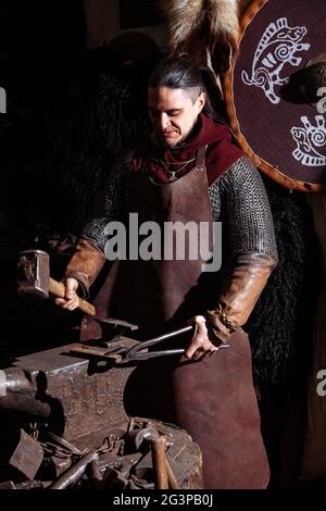 Viking forge des armes et des épées dans le smithy. Un homme dans les vêtements d'un guerrier est dans le smithy Banque D'Images