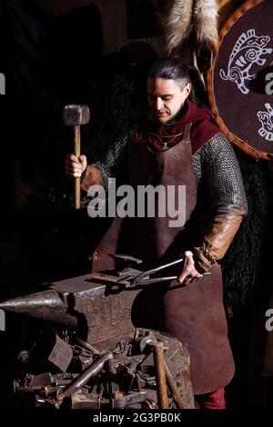 Viking forge des armes et des épées dans le smithy. Un homme dans les vêtements d'un guerrier est dans le smithy Banque D'Images