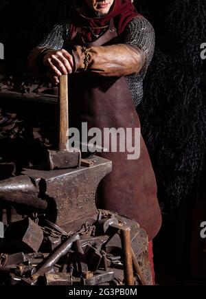 Viking forge des armes et des épées dans le smithy. Un homme dans les vêtements d'un guerrier est dans le smithy Banque D'Images