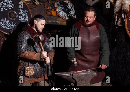 Viking forge des armes et des épées dans le smithy. Un homme dans les vêtements d'un guerrier est dans le smithy Banque D'Images