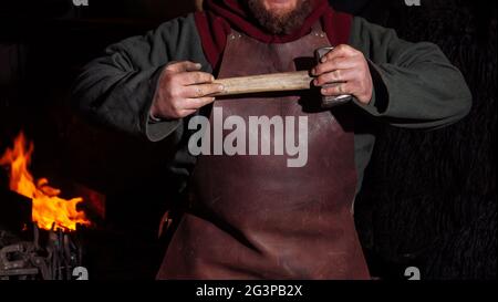 Viking forge des armes et des épées dans le smithy. Un homme dans les vêtements d'un guerrier est dans le smithy Banque D'Images