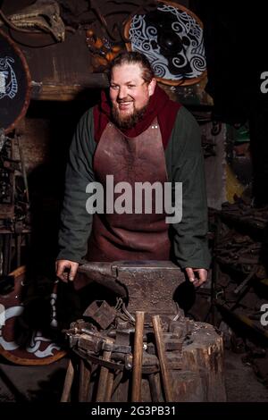 Viking forge des armes et des épées dans le smithy. Un homme dans les vêtements d'un guerrier est dans le smithy Banque D'Images