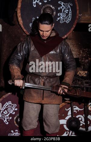 Viking forge des armes et des épées dans le smithy. Un homme dans les vêtements d'un guerrier est dans le smithy Banque D'Images