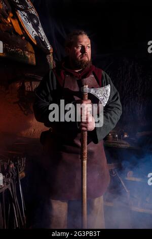 Armes et épées Viking forges dans la forge. Un homme en habits de guerrier est dans la forge sur l'arrière-plan de feu. Banque D'Images