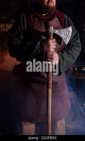 Armes et épées Viking forges dans la forge. Un homme en habits de guerrier est dans la forge sur l'arrière-plan de feu. Banque D'Images