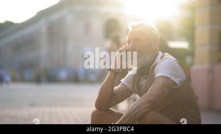 Un beau homme d'âge moyen communique au téléphone dans la ville pendant une journée d'été Banque D'Images