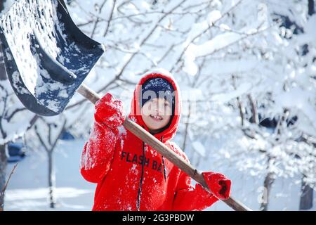 Portrait d'hiver extérieur d'un petit enfant heureux en bonne santé avec une pelle en main, déneigement Banque D'Images