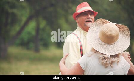 Homme âgé et femme dansant dans le jardin Banque D'Images