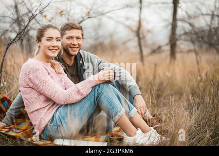 Un couple heureux assis sur le piconic Blanket à l'extérieur Banque D'Images