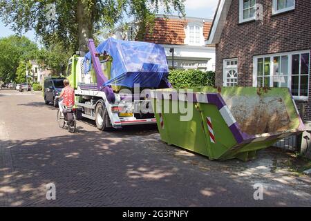Chariot avec saut industriel vert complet. Un saut vide sur le côté de la route dans un village hollandais. Pays-Bas, printemps, juin, Banque D'Images