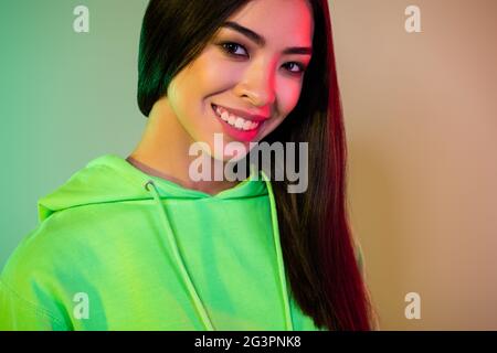 Portrait d'une fille gaie attrayante portant des vêtements sportifs posant un bon look isolé sur fond multicolore de lumière vive au néon Banque D'Images