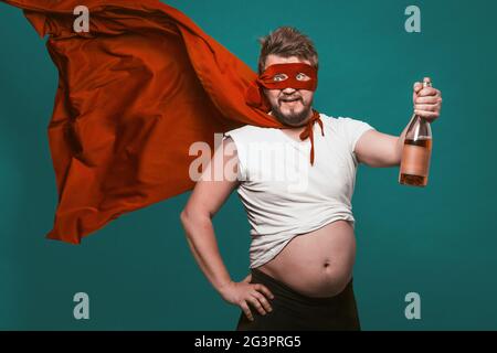 Saoul Super-héros ou antihéros Homme avec bouteille d'alcool, Homme en masque rouge de super-héros et cloaque flottant contenant une bouteille de vin Banque D'Images