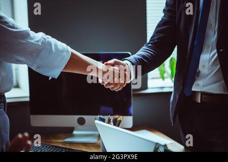 Homme d'affaires et femme d'affaires se secouent la main après le brainstorming d'équipe. Gros plan des mains d'hommes et de femmes contre de bureau int Banque D'Images