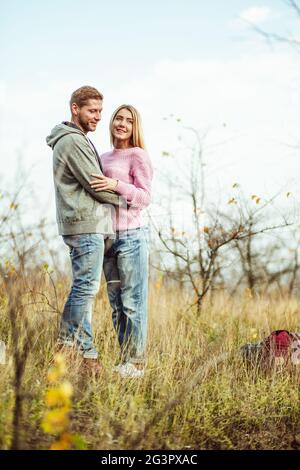 Il fait des câlins dans la nature. La jeune femme et l'homme se tient embrasser dans le champ contre le ciel du soir. Couple de touristes en pleine croissance Banque D'Images