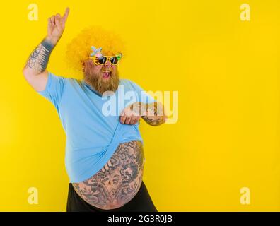 Gros homme avec perruque dans la tête et des danses de lunettes de soleil Banque D'Images