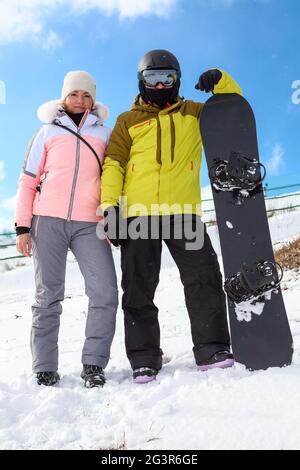 Couple aimant de snowboarders femme et homme se tiennent au sommet de la montagne, concept de sport d'hiver actif week-end, ciel bleu Banque D'Images