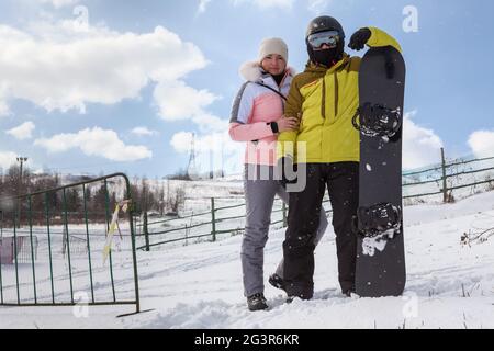 Un couple heureux de snowboarders se tient sur la pente de montagne dans la station de ski, l'espace de copie Banque D'Images