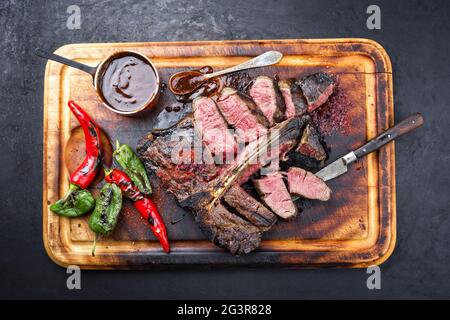 Griller au barbecue le steak de boeuf de porterhouse de Wagyu vieilli coupé en tranches avec un grand filet avec du piment et une sauce aux épices chaudes offerte en vue du dessus Banque D'Images