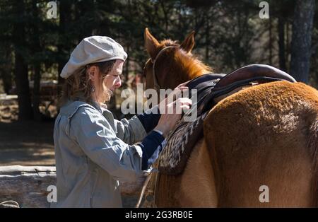 Femme rurale qui selles son cheval sur le terrain Banque D'Images