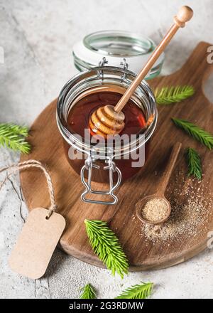 Pot de confiture maison de jeunes bourgeons de sapin, aiguilles et sucre naturel avec cuillère à miel en bois. Faire de la confiture d'épicéa à la maison. Banque D'Images