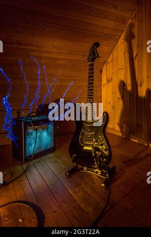 guitare électrique et amplificateur devant un arrière-plan en bois avec éclairage et effets de peinture légère Banque D'Images