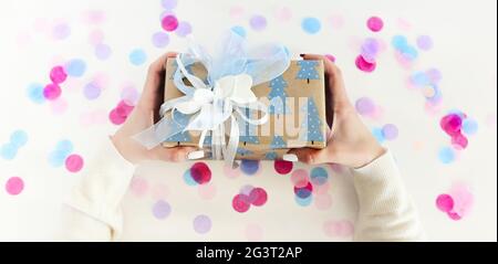 Petit femme portant une boîte cadeau sur des confettis Banque D'Images