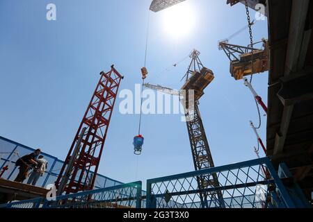 Nouvelle capitale administrative, Égypte. 17 juin 2021. Le 17 juin 2021, une grue de tour soulève du béton pour compléter la tour emblématique sur le site de construction du projet du quartier central des affaires (CBD) dans la nouvelle capitale administrative, en Égypte. Avec une vue imprenable sur les bâtiments modernes qui se trouvent dans le quartier des affaires (CBD) de la nouvelle capitale administrative de l'Égypte, les invités de Chine et d'Égypte ont organisé jeudi une cérémonie d'appoint pour la tour emblématique de 385 mètres de haut, qui sera le plus haut bâtiment d'Afrique une fois terminée. Credit: Sui Xiankai/Xinhua/Alay Live News Banque D'Images