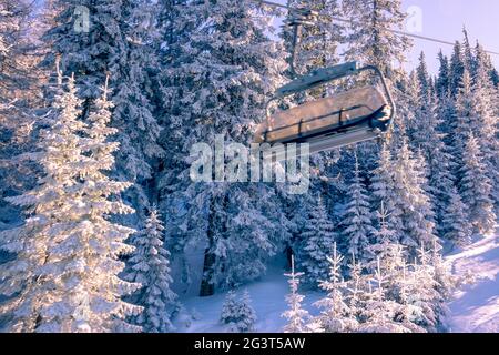 Cabine vide d'une remontée mécanique à l'arrière-plan d'une forêt de neige le matin Banque D'Images