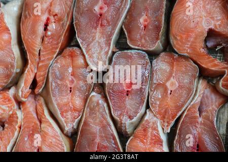 Des tranches de poisson rouge sont disposées en rangée. Résumé du saumon kéta ou saumon rose en gros plan. Banque D'Images