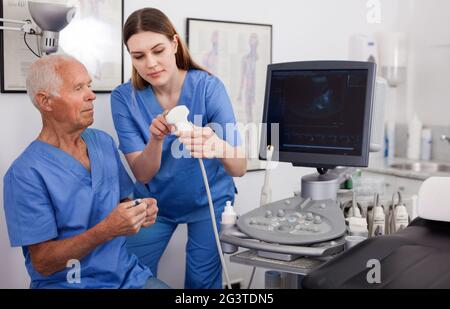 Portrait d'un jeune technicien montrant une nouvelle échographie au médecin en clinique Banque D'Images