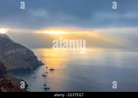 Rayons du soleil à travers de lourds nuages au-dessus de la Caldera de Santorin Banque D'Images