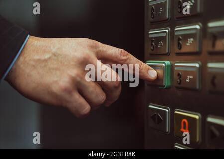 Gros plan de la main mâle appuie sur le bouton avec le braille pour aveugle. Gros plan. Main de l'employé de bureau dans le costume d'affaires presse le ele Banque D'Images