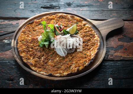 Lahmacun pizza turque traditionnelle avec salade sur table rustique en bois Banque D'Images