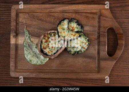 Délicieux champignons farcis aux épinards et au fromage sur fond de bois Banque D'Images