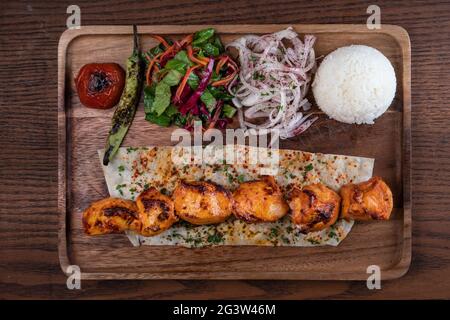 Poulet turc sis kebab avec du riz et des légumes sur une table en bois Banque D'Images