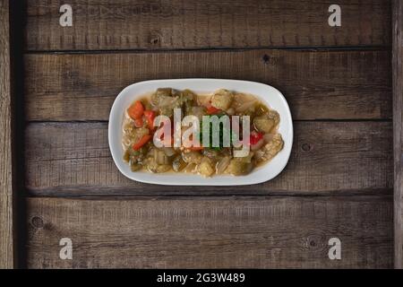 Tranches d'aubergines ou d'aubergines frites avec sauce salsa à la pâte de tomate et pommes de terre cubes sur une table de cuisine rustique en bois Banque D'Images