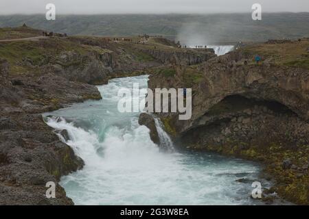 Touristes à la Godafoss (islandais : cascade des dieux) qui est une célèbre cascade en Islande. Banque D'Images