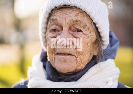 Portrait Femme caucasienne âgée avec cheveux gris et rides profondes 90 ans posant dans des vêtements chauds, écharpe tricotée blanche et ha Banque D'Images Portrait Femme caucasienne âgée avec cheveux gris et rides profondes 90 ans posant dans des vêtements chauds, écharpe tricotée blanche et ha Banque D'Images