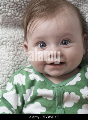 Mignon petit bébé jouant avec les mains et souriant Banque D'Images