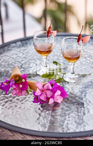 Cocktails d'été avec fleurs roses de bougainvilliers sur une table en verre. Concept été créatif. En été, fleurs surréalistes et boissons maison. Photo verticale Banque D'Images