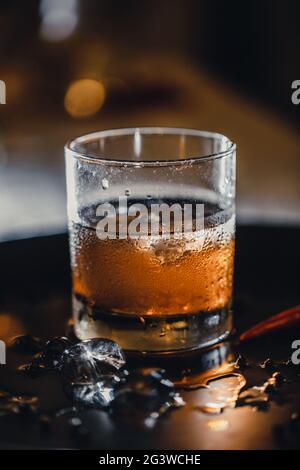 Cocktail - chuchoter avec de la glace en un coup. Bar cocktail whisky et cola. Glace froide dans un verre de whisky. Banque D'Images