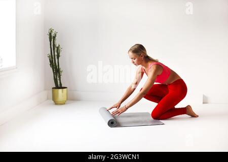 Femme en vêtements de sport préparant un tapis pour la leçon de yoga Banque D'Images