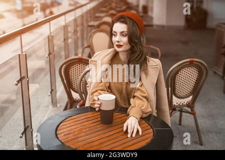 Tous les souvenirs sont réfléchis jeune parisienne femme assis à l'extérieur terrasse du restaurant donnant sur une tasse de café. Portrait Banque D'Images