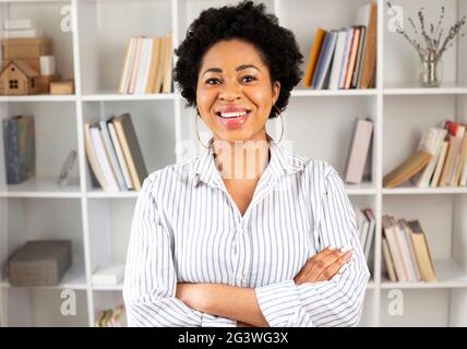 Portrait d'étudiante africaine souriante à l'intérieur avec des livres. Banque D'Images