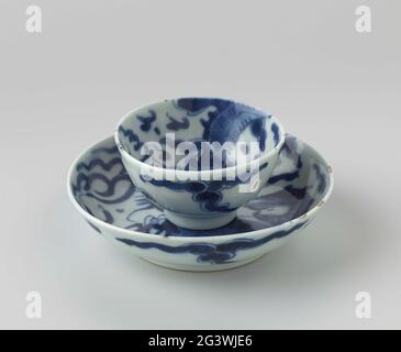 Tasse et soucoupe avec un Dragon de chasse aux perles. Tasse et soucoupe de porcelaine avec un mur légèrement étalant, peint en bleu sous-glaçure. À l'intérieur et à l'extérieur, un dragon à quatre puits de lumière continu une perle, la queue à l'extérieur et la tête à l'intérieur; le dragon est entouré de motifs nuages. Sur le dessous, un repère de joint est marqué d'un double cercle. Une puce dans le bord du plat. Bleu blanc. Banque D'Images