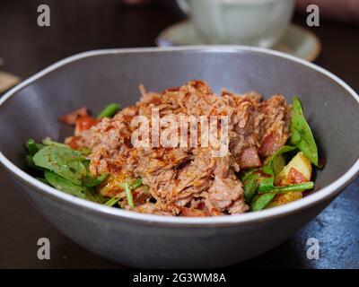 Photo en gros plan d'une salade de thon aux pommes de terre, aux tomates, aux épinards et aux haricots verts parsemés d'assaisonnement au paprika fumé Banque D'Images