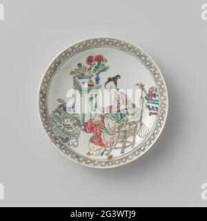 Soucoupe avec Lady, Boy et objets précieux. Plat de porcelaine, peint sur le glaçage en bleu, rose, vert, jaune, noir et or. Sur le plat, sur une chaise, une dame assise avec un garçon et un lapin, autour d'eux des symboles et des antiquités chanceux (vase avec des plumes de paon, un brûleur à encens, un doigt de citron, des rouleaux); sur le bord d'un pneu avec serviette. La paroi a été cassée. Famille Rose. Banque D'Images