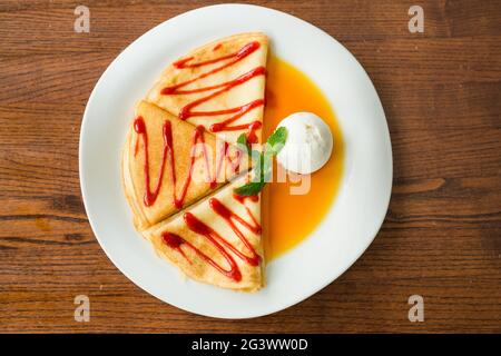 Trois crêpes sucrées avec confiture de cerise, miel et une cuillère froide de crème glacée. Concept - un plat de fête Banque D'Images