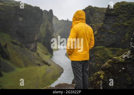 Homme en blouson jaune visitez le canyon volcanique de Fjadrargljufur en Islande, le jour de la pluie et de la fonte Banque D'Images